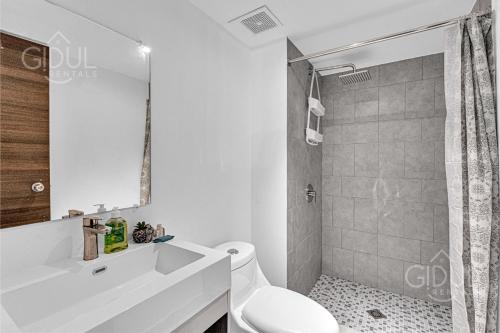 Un baño blanco con inodoro y ducha. en Cozy, Modern and Centric Apartment with pool and gym, en San Salvador