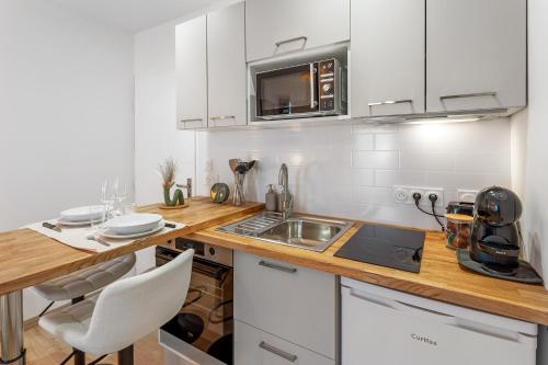 une cuisine avec des armoires blanches et un comptoir en bois dans l'établissement Centre-ville - Fibre - Netflix - Studio la Loire, à Savenay