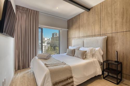 a bedroom with a large white bed with a window at Myla Roma Norte in Mexico City