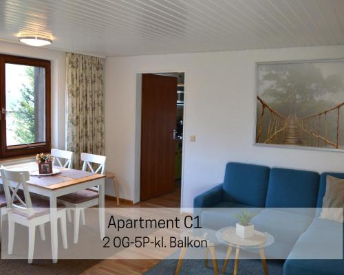 a living room with a blue couch and a table at Herbstliche Auszeit für Familien und Paare - Ferienhaus Albmatte in Feldbergnähe - direkt neben dem Radon Revitalbad mit Sauna und Therme in St. Blasien