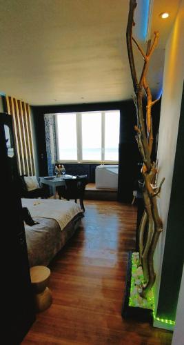 Cette chambre comprend un lit et un arbre. dans l'établissement Romantique Vue Face mer, à Berck-sur-Mer