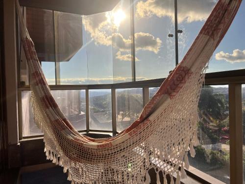 a hammock in a room with a large window at Apartamento com vista para o Vale dos Vinhedos in Bento Gonçalves