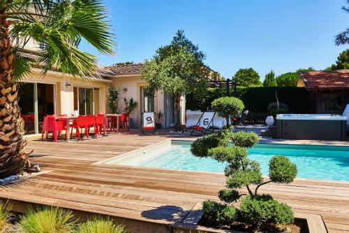 une maison avec une terrasse en bois et une piscine dans l'établissement la maison du bassin Piscine & Spa Andernos, à Andernos-les-Bains