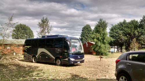 a blue bus parked in a field next to a car at Cabañas De Madera in La Unión