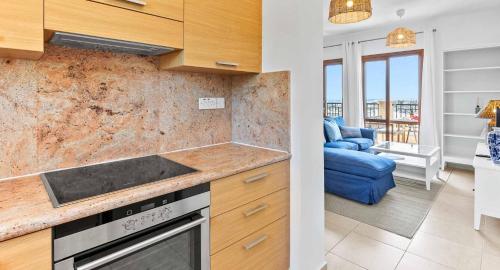 a kitchen with a stove top oven next to a living room at Beautiful Apartment BJ12 with Amazing Sea Views, Aphrodite Hills in Kouklia