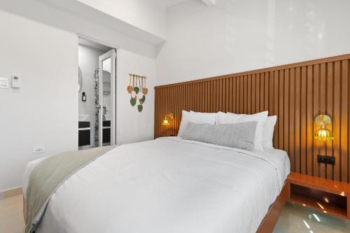 a bedroom with a large white bed with a wooden headboard at Ayana Inn PR in San Juan