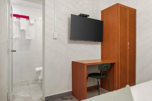 a bedroom with a desk with a tv on a wall at Ayana Inn PR in San Juan