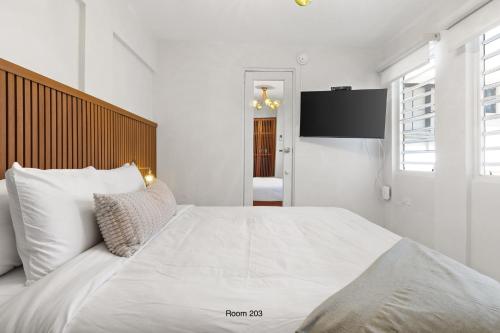 a white bedroom with a large bed and a flat screen tv at Ayana Inn PR in San Juan