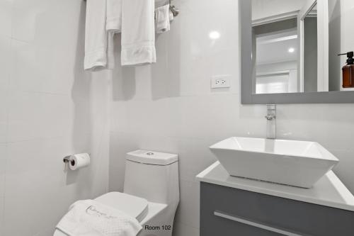 a white bathroom with a toilet and a sink at Ayana Inn PR in San Juan