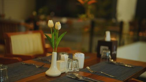 a table with two white vases with flowers on it at Blue Moon Hotel in Erbil