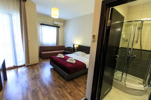 a bedroom with a bed and a couch and a shower at Lucic Rooms & Suites in Budva