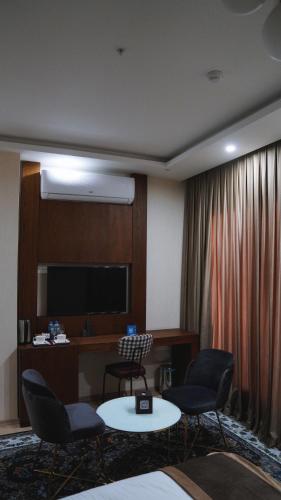 a hotel room with chairs and a table and a television at Blue Moon Hotel in Erbil