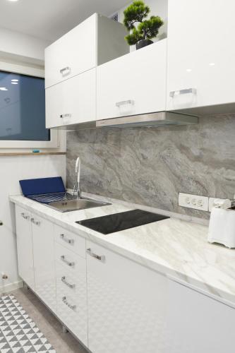 a kitchen with white cabinets and a sink at Champagne Apartments in Portorož