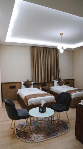 a hotel room with two beds and a table and chairs at Blue Moon Hotel in Erbil
