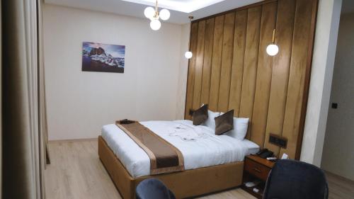 a bedroom with a bed with a wooden headboard at Blue Moon Hotel in Erbil
