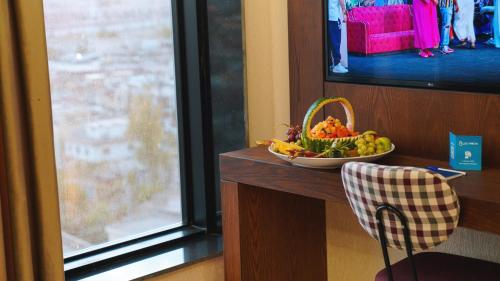 a bowl of fruit on a table next to a window at Blue Moon Hotel in Erbil