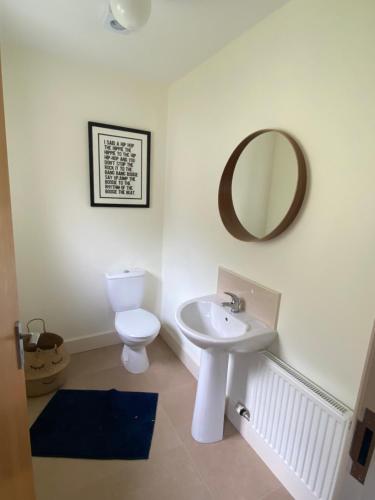 a bathroom with a sink and a toilet and a mirror at Beach House Inch in Inch