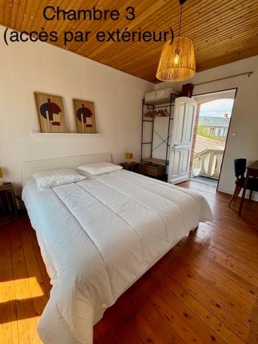 une chambre avec un grand lit blanc dans une pièce dans l'établissement Proche plage, maison de bourg pleine de charme, à Gouville-sur-Mer