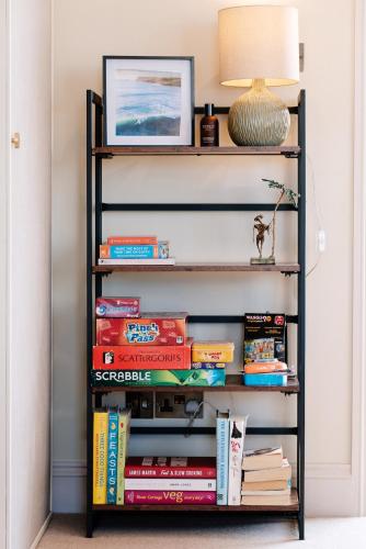 a book shelf filled with books and a lamp at Bijou Beachfront Gem, Rock in Padstow