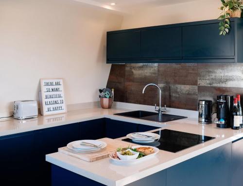 una cocina con fregadero y una barra con platos. en Bijou Beachfront Gem, Rock, en Padstow