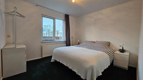 a white bedroom with a bed and a window at B&B MiRo in Rouveen