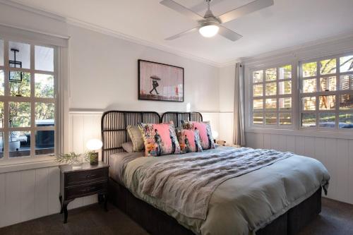 a bedroom with a bed with a ceiling fan and windows at Wrenwood Cottage- outdoor spa in serene setting in Daylesford