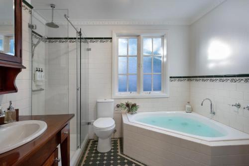 a bathroom with a tub and a toilet and a sink at Wrenwood Cottage- outdoor spa in serene setting in Daylesford
