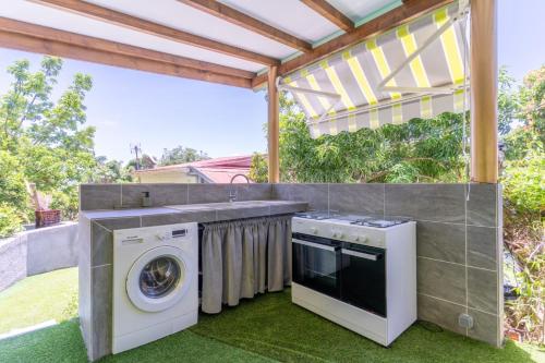 an outdoor kitchen with a washer and dryer on a patio at Bel'Eden Résidence Le Coin de L'Artiste in Le François