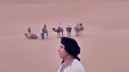a man standing in front of a group of horses in the desert at Oasis de Tiout in Tiout