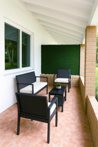 a patio with chairs and tables and a green wall at Central Miami Oasis, Near Brickell, Grove & Little Havana in Miami