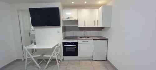 une cuisine avec des armoires blanches, une table et un évier dans l'établissement Studio centre ville de Gagny, à Gagny