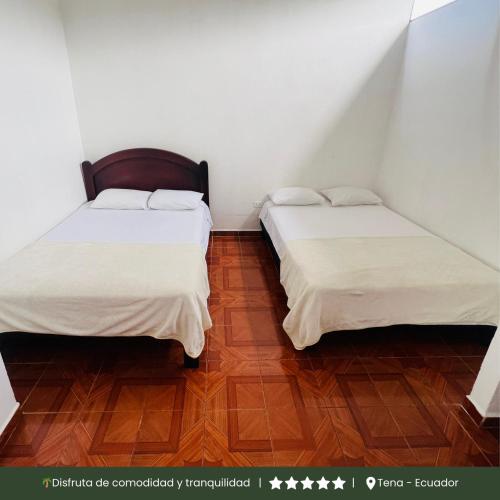 two beds in a small room with wooden floors at RinaKawsay - ViveViajando Apartamento amoblado en Tena in Tena