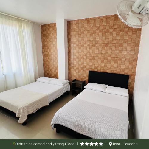 a bedroom with two beds and a brick wall at RinaKawsay - ViveViajando Apartamento amoblado en Tena in Tena
