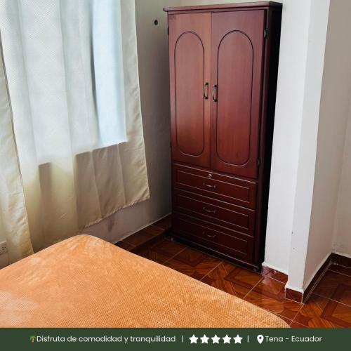 a bedroom with a wooden cabinet next to a window at RinaKawsay - ViveViajando Apartamento amoblado en Tena in Tena