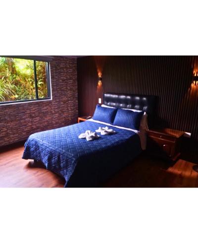 a bedroom with a bed with blue sheets and a window at Casa Campesina La Fagua in La Calera