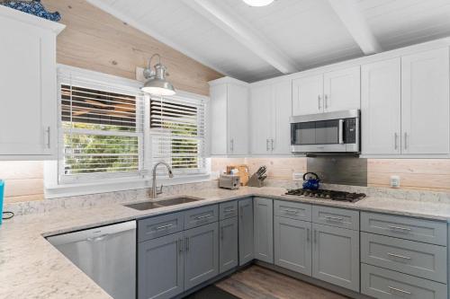 a kitchen with white cabinets and a sink and a microwave at Private Pool and Just a 3 Minute Walk to the Beach in Pawleys Island