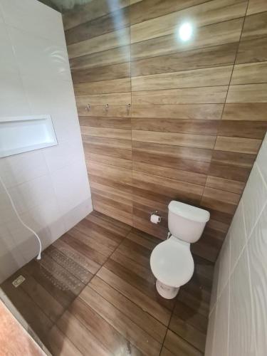 a small bathroom with a toilet and wooden walls at Casa com piscina em Itamaracá in Itamaracá