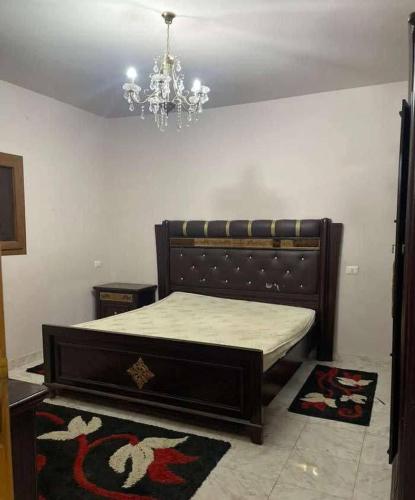 a bedroom with a bed with a chandelier and rug at kazbon House in Al Hāshimīyah