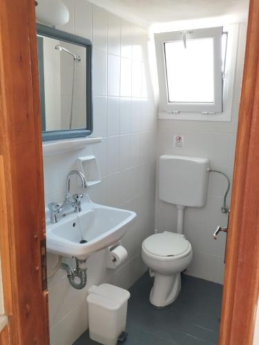 a bathroom with a toilet and a sink and a window at Hector's Studios in Alikanas