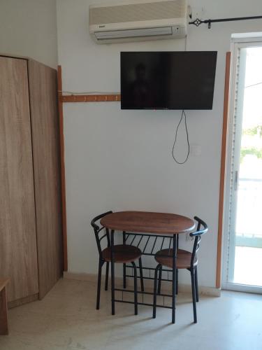 a dining room table with chairs and a television on a wall at Hector's Studios in Alikanas