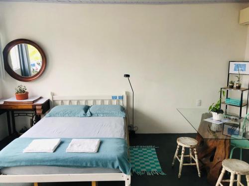 a bedroom with a bed and a mirror and stools at Pousada LUGAR - Quarto MAR familiar e tranquilo in Penha