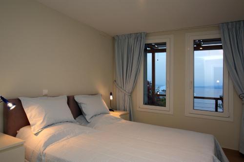 a bedroom with a white bed and two windows at Elies Houses in Agnontas