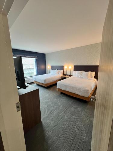 a hotel room with two beds and a flat screen tv at Home2 Suites By Hilton Bozeman Four Corners in Bozeman