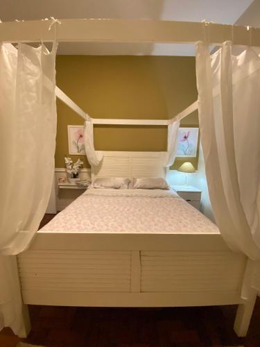 Un dormitorio con una cama con dosel y cortinas blancas. en Flamengo Vibes Stay & Shine in Rio, en Río de Janeiro