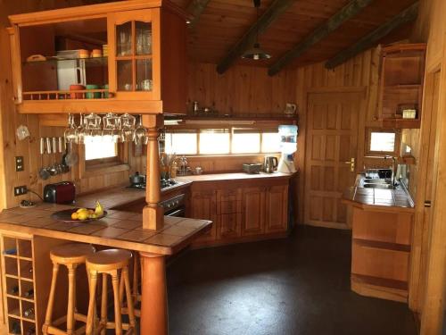 a kitchen with wooden cabinets and a island with bar stools at Tunquén, hermosa casa, cancha de tenis y piscina exclusivas in Tunquen