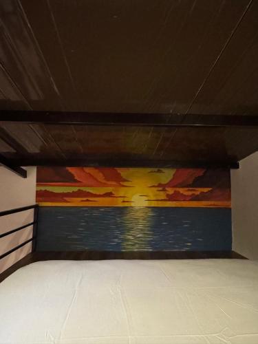 ein Schlafzimmer mit einem Gemälde an der Seite eines Bettes in der Unterkunft Departamentos confortables en Caacupé in Caacupé
