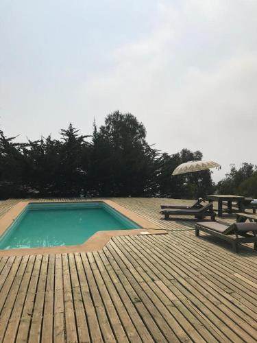 a swimming pool with a picnic table and an umbrella at Tunquén, hermosa casa, cancha de tenis y piscina exclusivas in Tunquen
