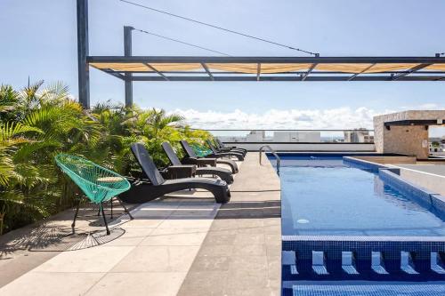 a row of chairs sitting next to a swimming pool at Central Playa del Carmen Master Suite with rooftop pool and gym WiFi free parking near beach in Playa del Carmen