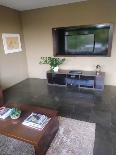a living room with a television and a coffee table at Flat encantador com lazer in Serra Negra