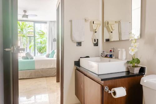 a bathroom with a sink and a mirror and a bed at Central Playa del Carmen Master Suite with rooftop pool and gym WiFi free parking near beach in Playa del Carmen